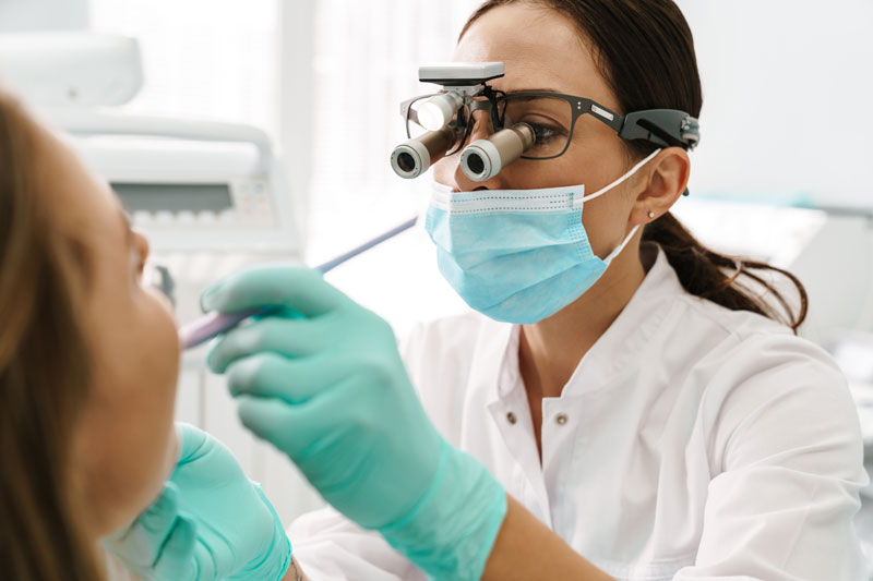 a dentist checking a patients implant with microscopes and tools